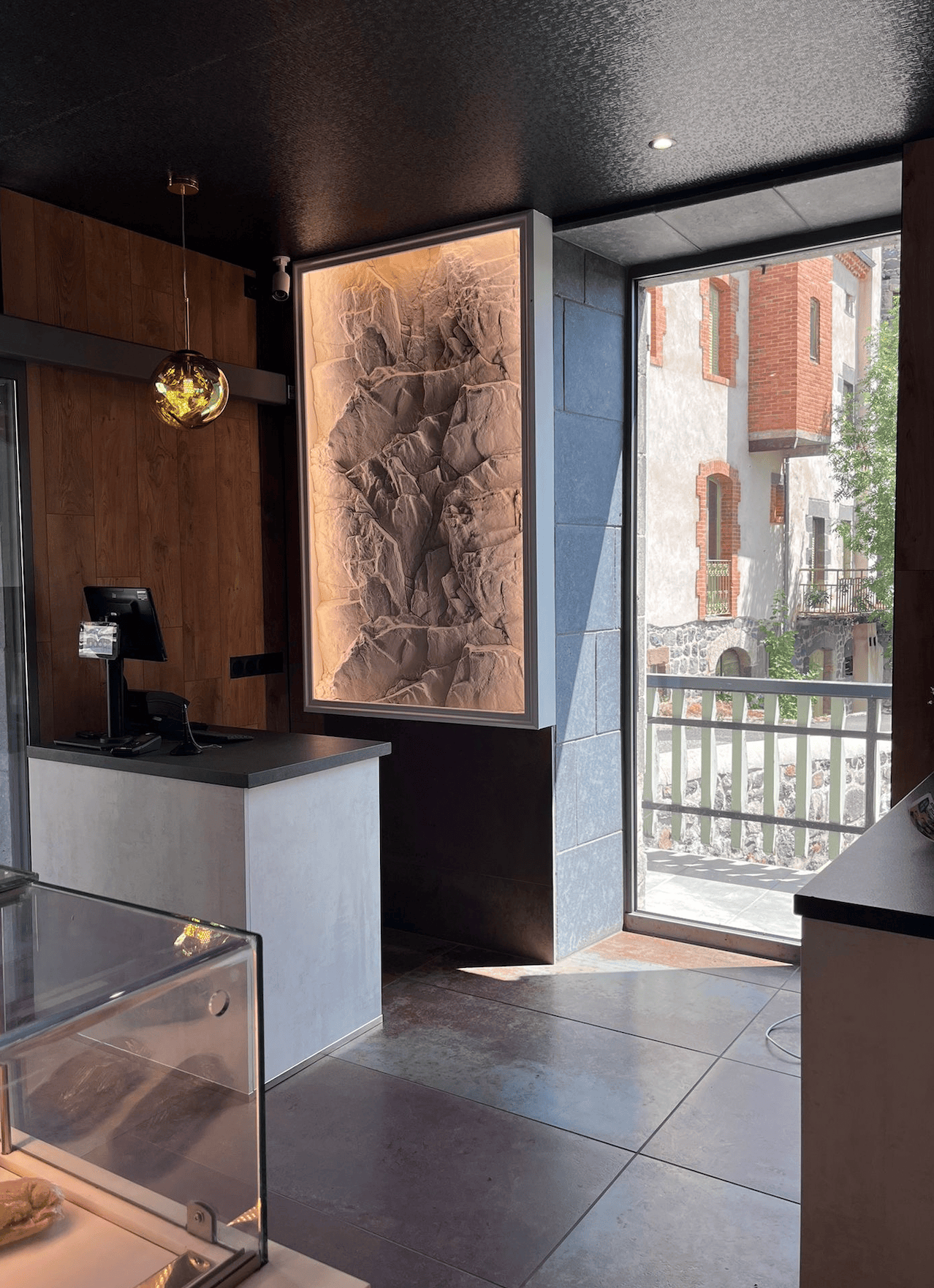 Niche encadrée en panneau effet pierre derrière la caisse d'une boutique